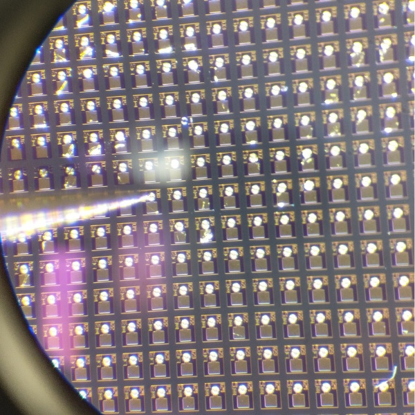 A laser wafer viewed through a microscope, showing hundreds of individual dies in a regular array